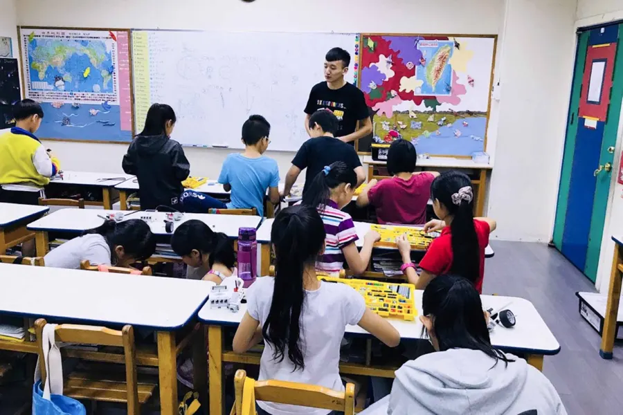 老師在國小教室帶營隊，學生分組組裝樂高