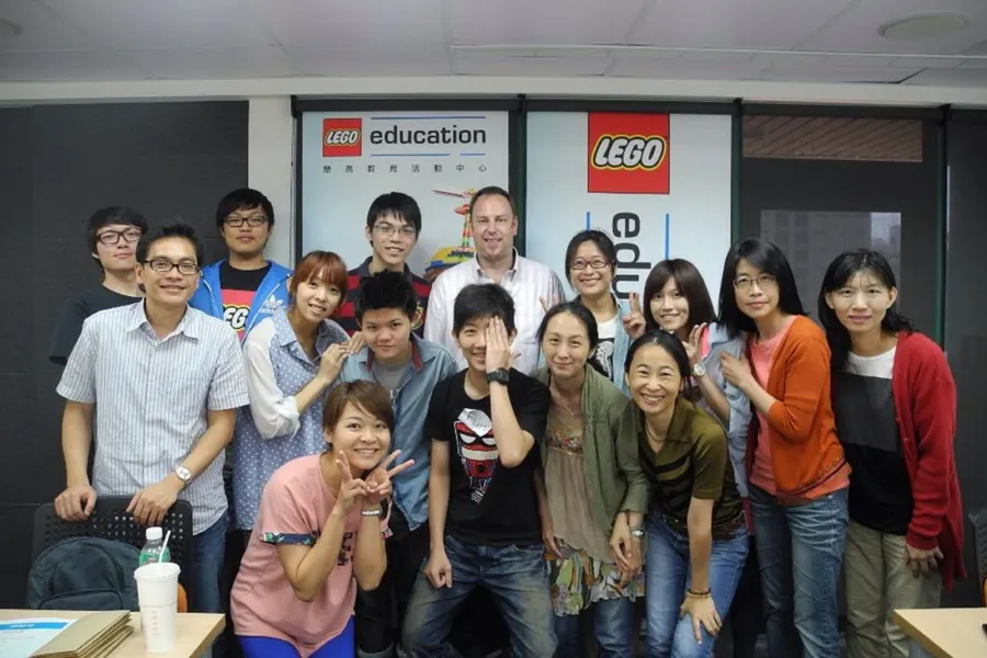 玩樂高手老師與合作夥伴在 LEGO Education 背板前合照