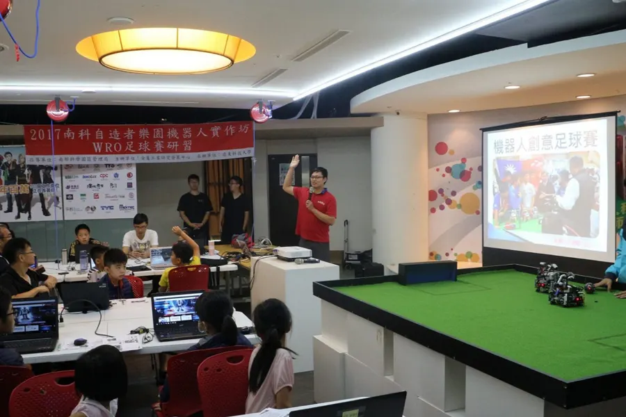 WRO 足球賽專題研習現場，學員看著投影與比賽場地